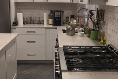 ニューヨークにあるお手頃価格の小さなコンテンポラリースタイルのおしゃれなキッチン (アンダーカウンターシンク、シェーカースタイル扉のキャビネット、白いキャビネット、珪岩カウンター、白いキッチンパネル、サブウェイタイルのキッチンパネル、シルバーの調理設備、濃色無垢フローリング、アイランドなし、グレーの床) の写真
