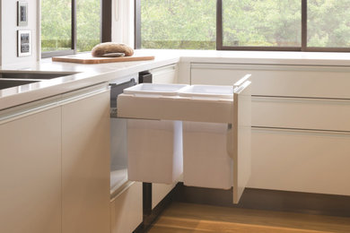 Diseño de cocinas en U contemporáneo con puertas de armario blancas, encimera de cuarzo compacto, suelo de madera clara y encimeras blancas