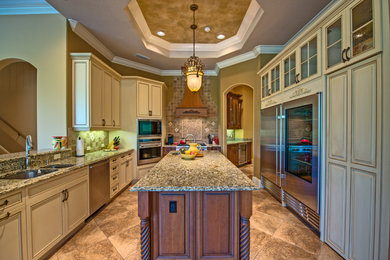 Large tuscan galley ceramic tile and beige floor enclosed kitchen photo in Tampa with an undermount sink, raised-panel cabinets, beige cabinets, granite countertops, beige backsplash, ceramic backsplash, stainless steel appliances and an island