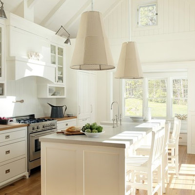 Inspiration for a coastal galley kitchen remodel in Boston with raised-panel cabinets, white cabinets, concrete countertops, white backsplash and paneled appliances