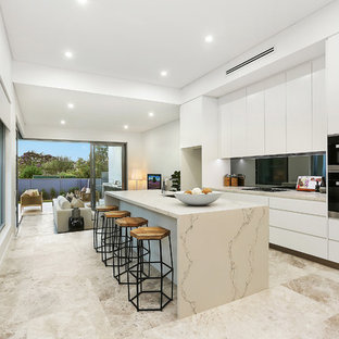 Design ideas for a contemporary galley kitchen in Sydney with an undermount sink, flat-panel cabinets, white cabinets, metallic splashback, mirror splashback, black appliances, with island, beige floor and beige benchtop.