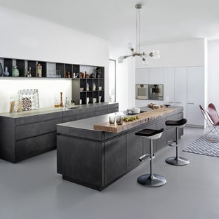 This is an example of a large country eat-in kitchen in Boston with an undermount sink, flat-panel cabinets, distressed cabinets, concrete benchtops, white splashback, panelled appliances and with island.