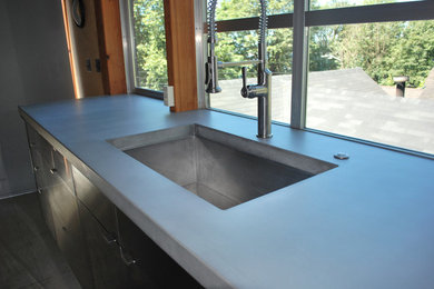 Inspiration for a mid-sized contemporary single-wall concrete floor and gray floor open concept kitchen remodel in Seattle with an undermount sink, flat-panel cabinets, stainless steel cabinets, concrete countertops, stainless steel appliances, no island and gray countertops