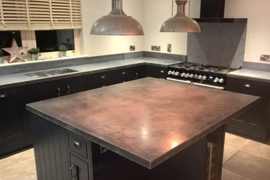 Photo of a contemporary kitchen in Other with a double-bowl sink, black cabinets, concrete worktops, an island, grey floors and grey worktops.