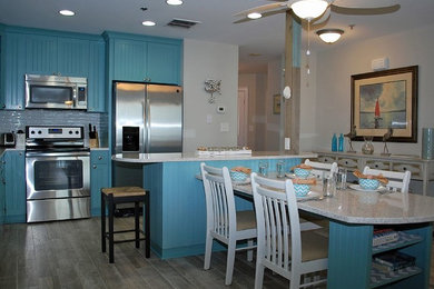 Inspiration for a coastal galley eat-in kitchen remodel in Other with recessed-panel cabinets, turquoise cabinets, granite countertops and two islands