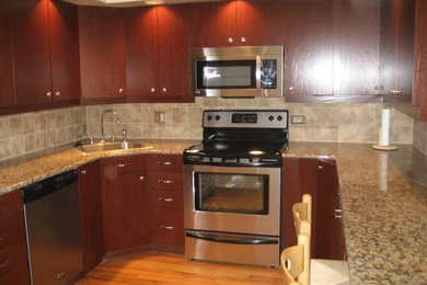 Bild på ett funkis kök, med en nedsänkt diskho, släta luckor, röda skåp, granitbänkskiva, beige stänkskydd, stänkskydd i keramik, rostfria vitvaror och mellanmörkt trägolv