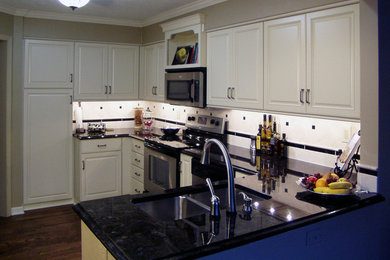 Inspiration for a mid-sized timeless u-shaped dark wood floor enclosed kitchen remodel in Cleveland with a double-bowl sink, raised-panel cabinets, white cabinets, granite countertops, white backsplash, ceramic backsplash and stainless steel appliances