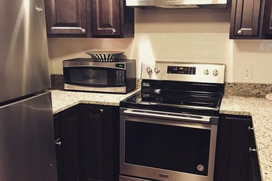Example of a small mountain style u-shaped bamboo floor and brown floor enclosed kitchen design in Boston with raised-panel cabinets, granite countertops, white backsplash, subway tile backsplash, stainless steel appliances, no island and gray countertops