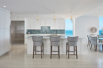 Inspiration for a large classic single-wall open plan kitchen in Miami with a single-bowl sink, shaker cabinets, white cabinets, quartz worktops, blue splashback, glass tiled splashback, stainless steel appliances, porcelain flooring, an island and blue worktops.