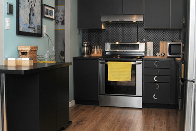 Example of a mid-sized trendy brown floor kitchen design in Toronto with a single-bowl sink, flat-panel cabinets, black cabinets, black backsplash, ceramic backsplash, stainless steel appliances and black countertops