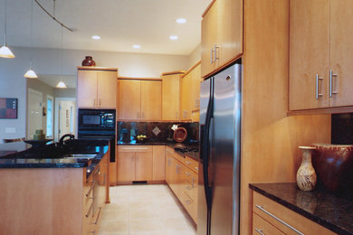 На фото: большая прямая кухня-гостиная в современном стиле с плоскими фасадами, светлыми деревянными фасадами, гранитной столешницей, черным фартуком, техникой из нержавеющей стали, полом из керамической плитки и островом