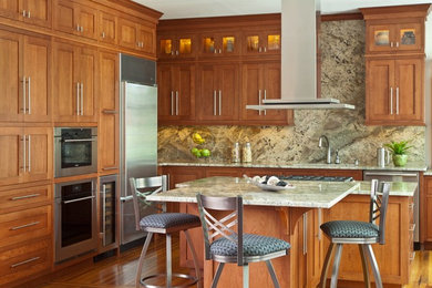Exemple d'une cuisine en bois brun avec un évier encastré, un placard à porte shaker, un plan de travail en granite, une crédence en dalle de pierre, un électroménager en acier inoxydable et îlot.
