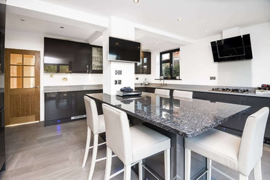 Inspiration for a large contemporary u-shaped enclosed kitchen in London with an integrated sink, shaker cabinets, grey cabinets, granite worktops, white splashback, glass tiled splashback, integrated appliances, porcelain flooring and an island.