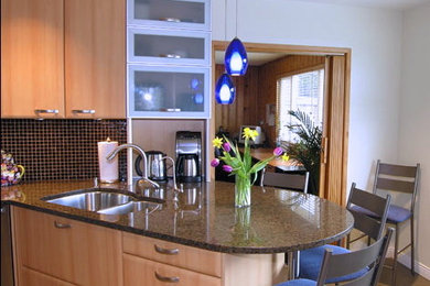 Photo of a medium sized traditional u-shaped enclosed kitchen in Vancouver with a submerged sink, flat-panel cabinets, light wood cabinets, granite worktops, brown splashback, glass sheet splashback, stainless steel appliances, ceramic flooring and a breakfast bar.