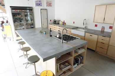 Large minimalist single-wall concrete floor and gray floor eat-in kitchen photo in Denver with concrete countertops, an island, a farmhouse sink, flat-panel cabinets, light wood cabinets and gray countertops