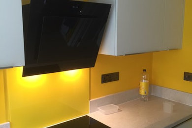 Design ideas for a contemporary kitchen in Hampshire with white cabinets, laminate countertops and yellow splashback.