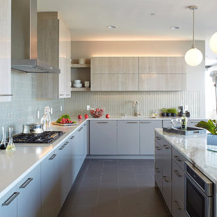 Photo of an expansive contemporary l-shaped kitchen in New York with an undermount sink, flat-panel cabinets, grey cabinets, quartz benchtops, grey splashback, glass tile splashback, stainless steel appliances, porcelain floors, with island, grey floor and white benchtop.