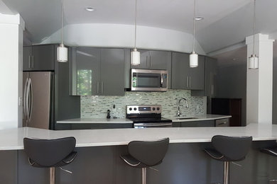 Example of a mid-sized trendy galley laminate floor and brown floor eat-in kitchen design in Birmingham with an undermount sink, flat-panel cabinets, gray cabinets, quartz countertops, multicolored backsplash, glass sheet backsplash, stainless steel appliances, an island and white countertops