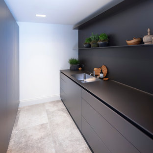 Design ideas for a small contemporary open plan kitchen in Cheshire with an integrated sink, flat-panel cabinets, black cabinets, laminate benchtops, black splashback, porcelain floors, no island, grey floor and black benchtop.