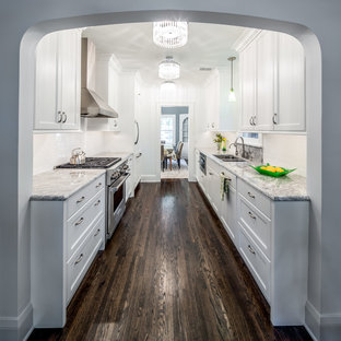 Exemple d'une cuisine parallèle chic fermée et de taille moyenne avec un évier encastré, un placard à porte shaker, une crédence blanche, des portes de placard blanches, un plan de travail en granite, une crédence en carrelage métro, un sol en bois foncé, aucun îlot et un sol marron.