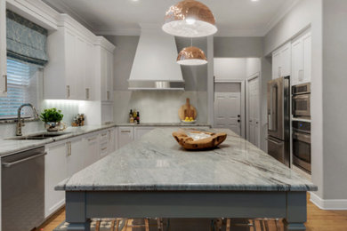 Open concept kitchen - mid-sized transitional l-shaped medium tone wood floor and brown floor open concept kitchen idea in Miami with an undermount sink, recessed-panel cabinets, white cabinets, marble countertops, white backsplash, glass tile backsplash, stainless steel appliances and an island