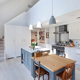 Ispirazione per una cucina scandinava con lavello stile country, ante in stile shaker, ante bianche, elettrodomestici in acciaio inossidabile, parquet chiaro e isola