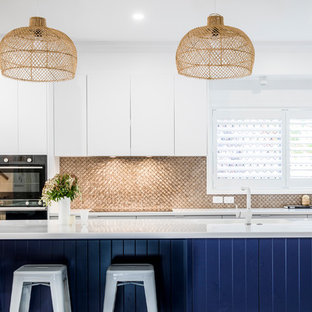 Photo of a mid-sized contemporary galley open plan kitchen in Townsville with an undermount sink, flat-panel cabinets, blue cabinets, quartz benchtops, metallic splashback, mosaic tile splashback, stainless steel appliances, with island and white benchtop.