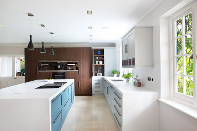 Inspiration for a medium sized contemporary l-shaped kitchen in Kent with a double-bowl sink, recessed-panel cabinets, blue cabinets, stainless steel appliances, an island, beige floors and white worktops.