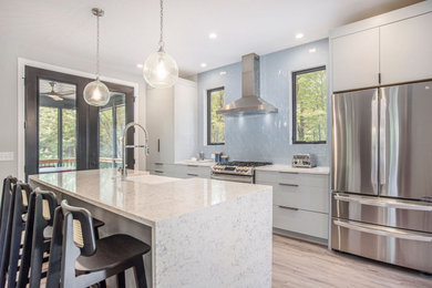 Inspiration for a retro kitchen in Grand Rapids with grey cabinets, engineered stone countertops, blue splashback, stainless steel appliances, vinyl flooring, an island, brown floors and white worktops.