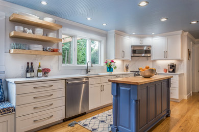 Kitchen - farmhouse l-shaped medium tone wood floor and brown floor kitchen idea in Boston with an undermount sink, recessed-panel cabinets, white cabinets, marble countertops, white backsplash, marble backsplash, stainless steel appliances, an island and white countertops