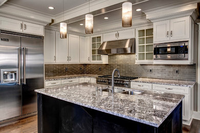 Example of a trendy kitchen design in Seattle with a double-bowl sink, shaker cabinets, white cabinets, glass tile backsplash and an island