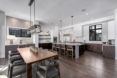 Inspiration for a large contemporary u-shaped dark wood floor and brown floor kitchen remodel in Denver with an undermount sink, dark wood cabinets, white backsplash, ceramic backsplash, stainless steel appliances, white countertops, flat-panel cabinets and an island