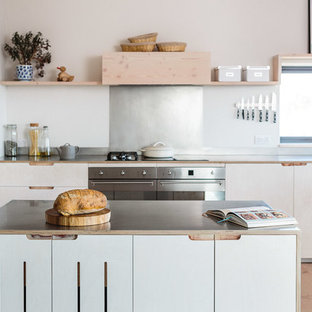 Immagine di una cucina scandinava di medie dimensioni con lavello stile country, ante lisce, ante in legno chiaro, top in acciaio inossidabile, paraspruzzi a effetto metallico, elettrodomestici in acciaio inossidabile, parquet chiaro e isola