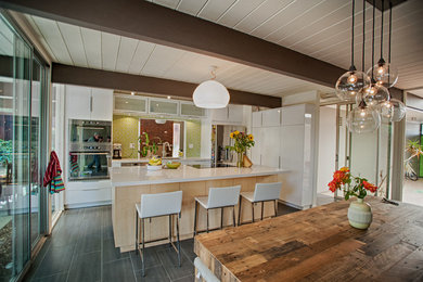 Eat-in kitchen - contemporary single-wall porcelain tile eat-in kitchen idea in San Francisco with an undermount sink, flat-panel cabinets, white cabinets, solid surface countertops, green backsplash, mosaic tile backsplash, stainless steel appliances and an island