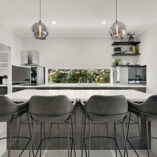 Contemporary kitchen in Brisbane with quartz benchtops, stainless steel appliances, porcelain floors, with island, beige floor and white benchtop.