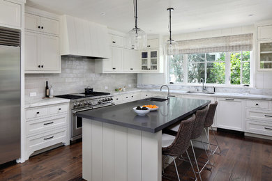 Example of a country l-shaped dark wood floor and brown floor kitchen design in San Francisco with an undermount sink, shaker cabinets, white cabinets, white backsplash, stainless steel appliances, an island and white countertops