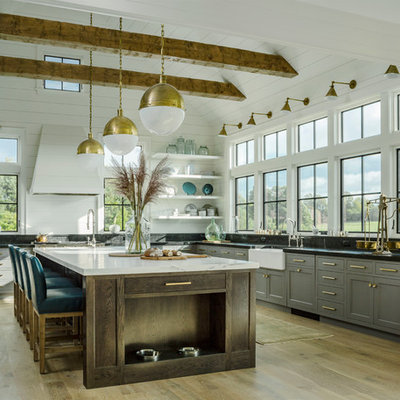 Example of a country l-shaped light wood floor kitchen design in Burlington with a farmhouse sink, shaker cabinets, gray cabinets and an island