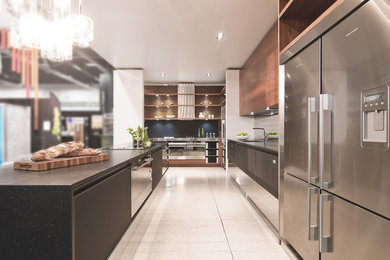 This is an example of a large contemporary l-shaped kitchen in Vancouver with a submerged sink, flat-panel cabinets, black cabinets, mosaic tiled splashback, stainless steel appliances, porcelain flooring and an island.