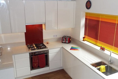 This is an example of a medium sized contemporary kitchen in Buckinghamshire with a submerged sink, white cabinets, quartz worktops, red splashback, glass sheet splashback and vinyl flooring.