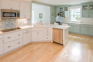 Imagen de cocina actual de tamaño medio abierta sin isla con puertas de armario blancas y electrodomésticos de acero inoxidable