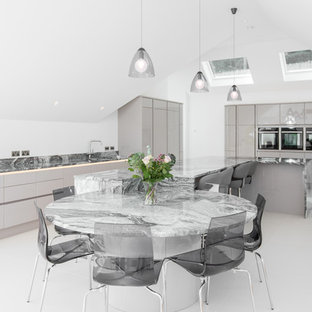 Contemporary kitchen in Cornwall with a submerged sink, flat-panel cabinets, grey cabinets, marble worktops, grey splashback, marble splashback, black appliances, an island, white floors and grey worktops.
