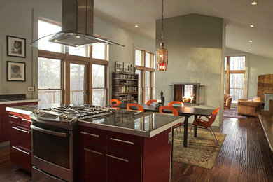 Photo of a contemporary u-shaped kitchen/diner in Boston with flat-panel cabinets, red cabinets, marble worktops, stainless steel appliances, medium hardwood flooring and an island.