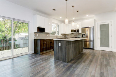 Example of a mid-sized trendy l-shaped bamboo floor and brown floor open concept kitchen design in DC Metro with an undermount sink, flat-panel cabinets, dark wood cabinets, quartzite countertops, gray backsplash, ceramic backsplash, stainless steel appliances, an island and white countertops