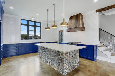 Open concept kitchen - mid-sized contemporary u-shaped concrete floor and beige floor open concept kitchen idea in New Orleans with an undermount sink, recessed-panel cabinets, blue cabinets, solid surface countertops, white backsplash, subway tile backsplash, stainless steel appliances and an island