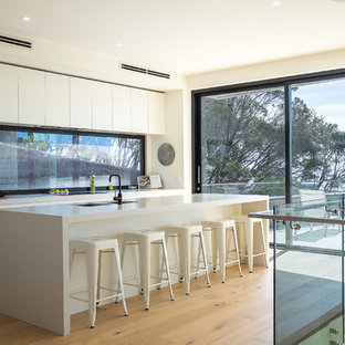 This is an example of a contemporary galley kitchen in Melbourne with an undermount sink, white cabinets, with island, window splashback, medium hardwood floors, brown floor and recessed-panel cabinets.