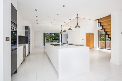 Design ideas for a large contemporary open plan kitchen in Gloucestershire with engineered stone countertops, ceramic flooring, an island, white floors and white worktops.