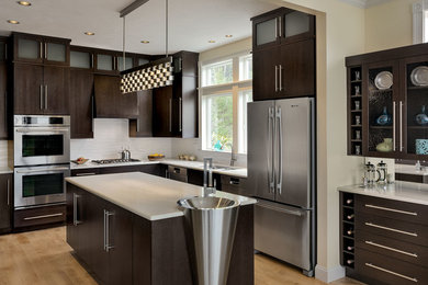 Example of a mid-sized trendy u-shaped light wood floor enclosed kitchen design in Portland Maine with flat-panel cabinets, dark wood cabinets, beige backsplash, stainless steel appliances, an island, marble countertops, porcelain backsplash and an undermount sink