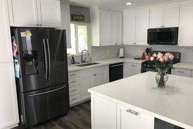 Example of a mid-sized trendy l-shaped dark wood floor and brown floor open concept kitchen design in Los Angeles with an undermount sink, shaker cabinets, white cabinets, quartzite countertops, white backsplash, subway tile backsplash, stainless steel appliances, an island and white countertops