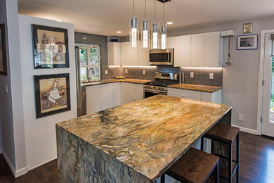 Open concept kitchen - large contemporary l-shaped dark wood floor and brown floor open concept kitchen idea in Other with an undermount sink, flat-panel cabinets, white cabinets, onyx countertops, gray backsplash, glass tile backsplash, stainless steel appliances and an island