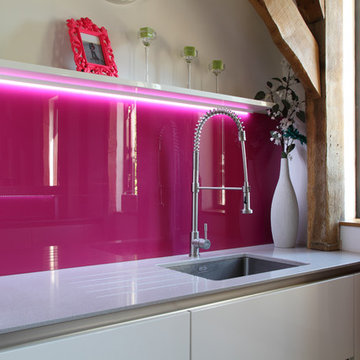 Contemporary kitchen by John Ladbury-  pink splash-back. Barn conversion